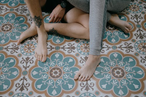 Free Crop couple sitting with crossed legs on floor Stock Photo