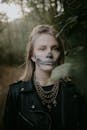 森林里，一位年轻女子涂着骷髅脸，穿着皮夹克，非常适合万圣节