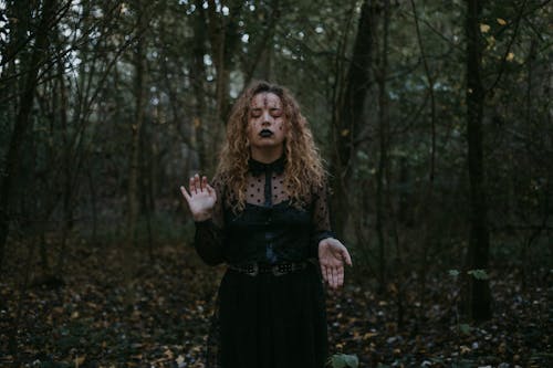 Woman in Black Dress Standing in the Middle of a Forest