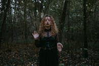 一名卷发黑衣女子站在黑暗神秘的森林中