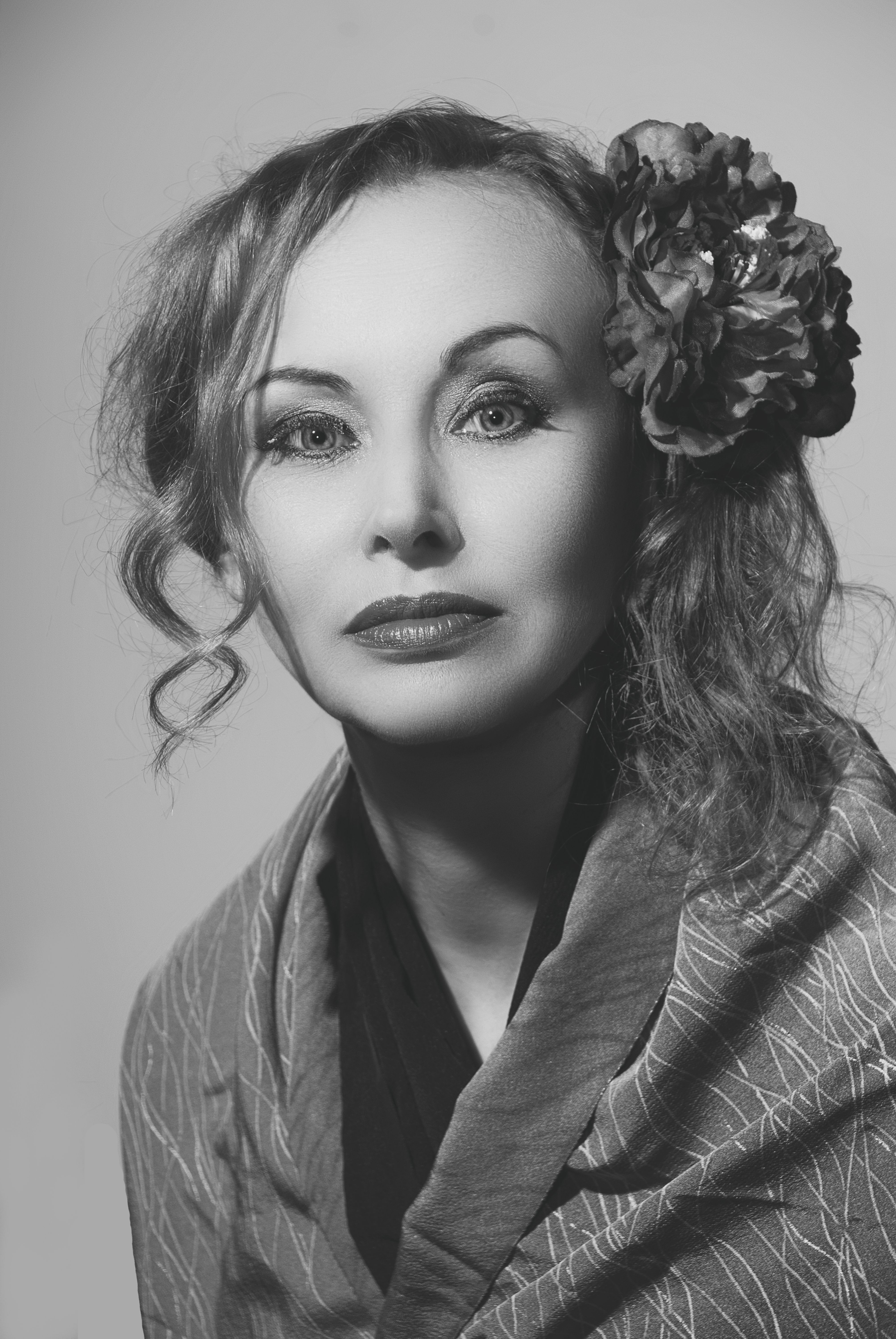 Classic black-and-white headshot of a woman with a floral accessory.