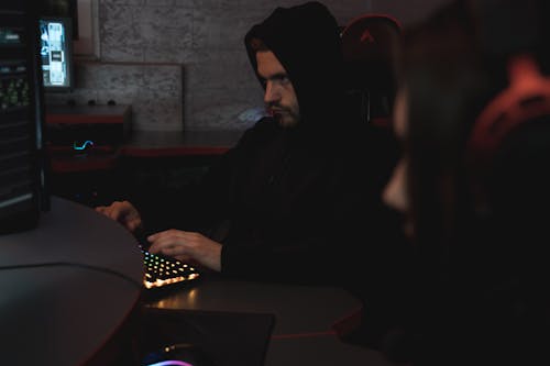 Man in Black Hoodie Sitting on Chair while Using Computer