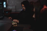 Man in Black Hoodie Sitting on Chair while Using Computer