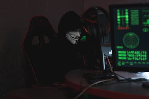 Free Person Wearing a Mask Sitting on CHair while Using a Computer Stock Photo