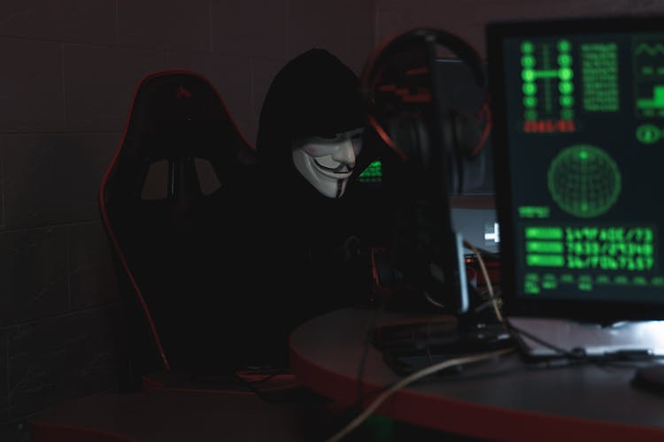 Person Wearing A Mask Sitting On CHair While Using A Computer