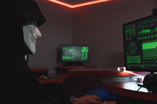 Free A Person with Mask Using a Computer Stock Photo