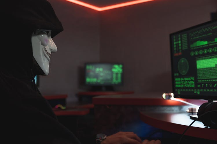 A Person With Mask Using A Computer