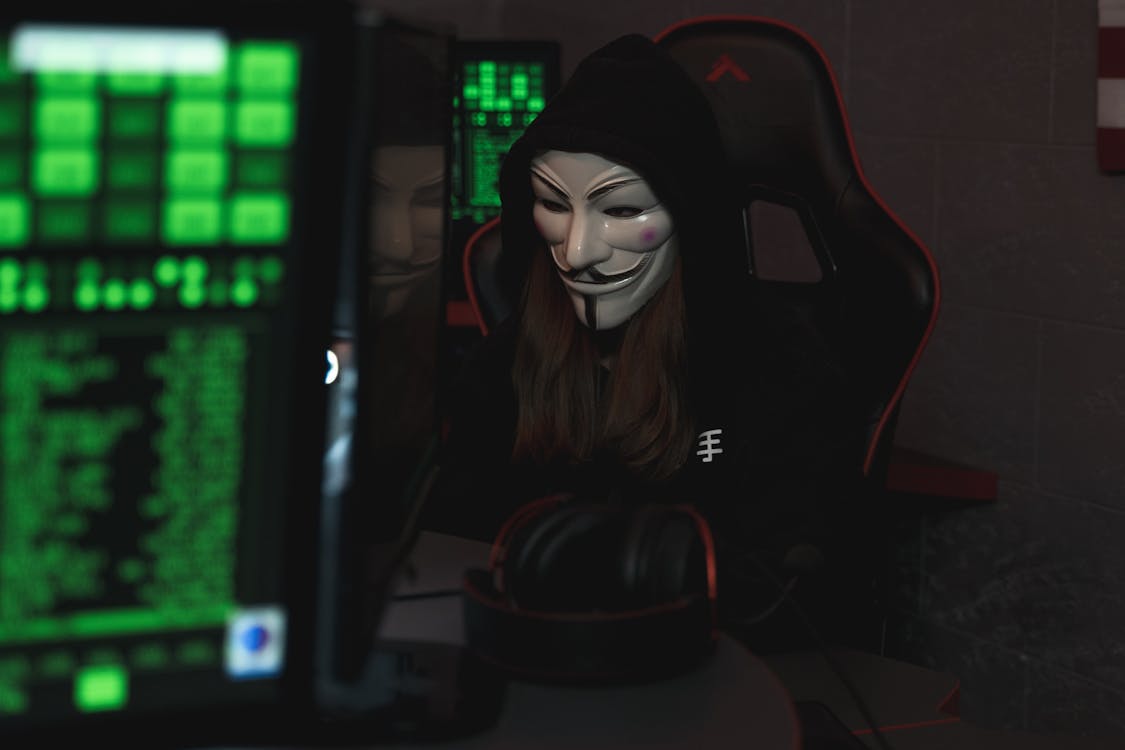 Free Person with Mask Sitting while Using a Computer Stock Photo