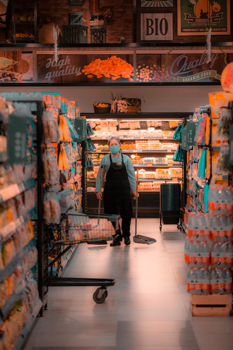 Elderly Woman Carrying Dustpans In A Grocery Store