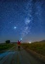 Man in Red Shirt Standing on Country Road while Looking at the Stars in the Sky
