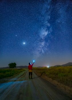 在伊朗萨瓦乡村，一名男子站在星空下的乡间小路上