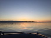 平静的湖面上映着宁静的日落，地平线处有一艘船的剪影