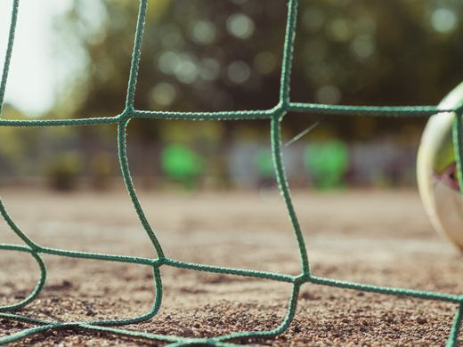 A ball resting against the goal net at ground level — photo by Tembela Bohle on Pexels