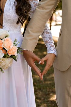 Heart-shaped hands symbolize love and union at an outdoor wedding ceremony.