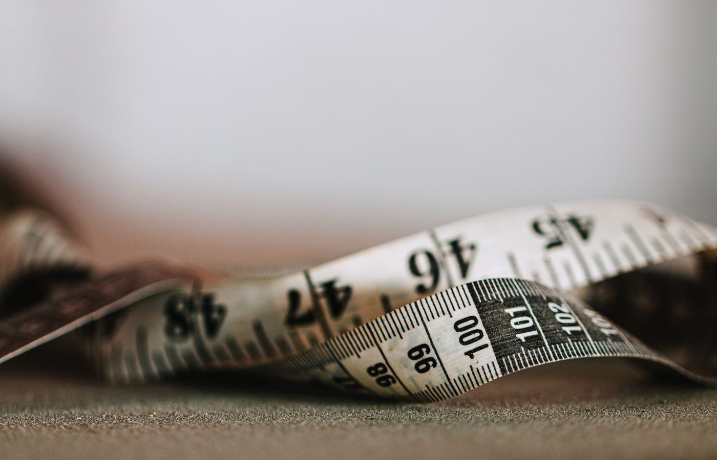 Artistic shallow focus image of a measuring tape showing numbers and units.