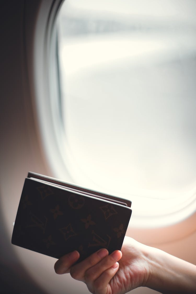 Crop Faceless Woman Showing Passport Against Airplane Viewing Window