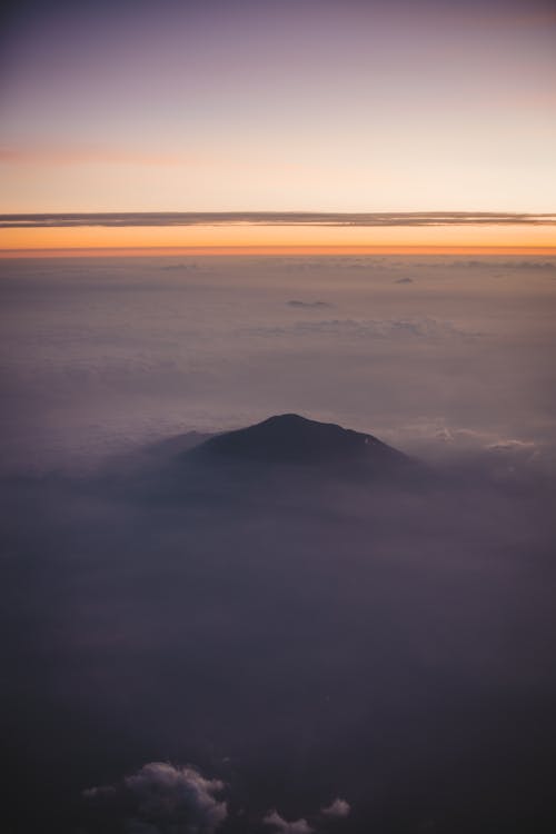 Free From aircraft view of majestic hill peak under clouds Stock Photo