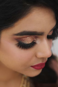 Elegant close-up of a woman with glitter eyeshadow, bold eyelashes, and red lips.