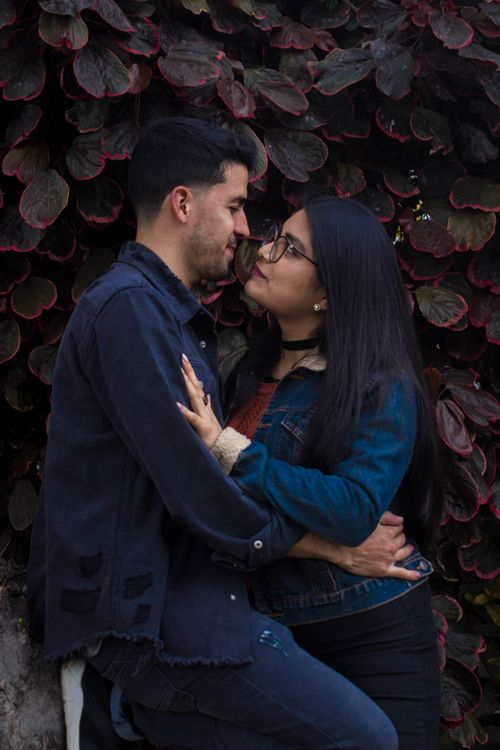 Free A loving couple embraces romantically in front of vibrant foliage, highlighting a moment of intimacy. Stock Photo