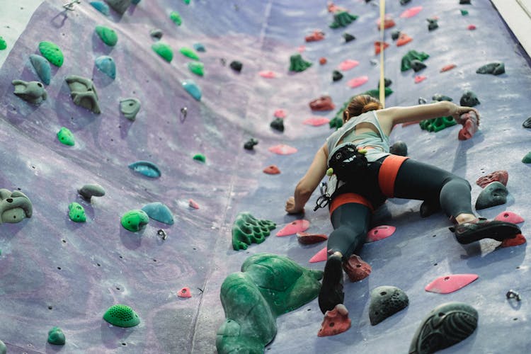 Female Sportsman Training Climbing On Rock Climbing Wall At Gym