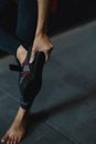 Anonymous person in sports leggings standing with raised leg and taking off shoes