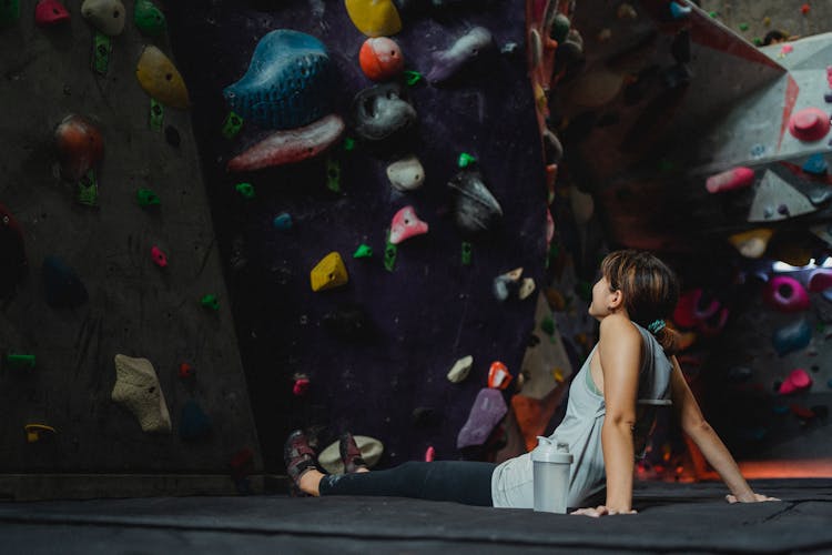 Woman Resting On Sports Mat In Climbing Center