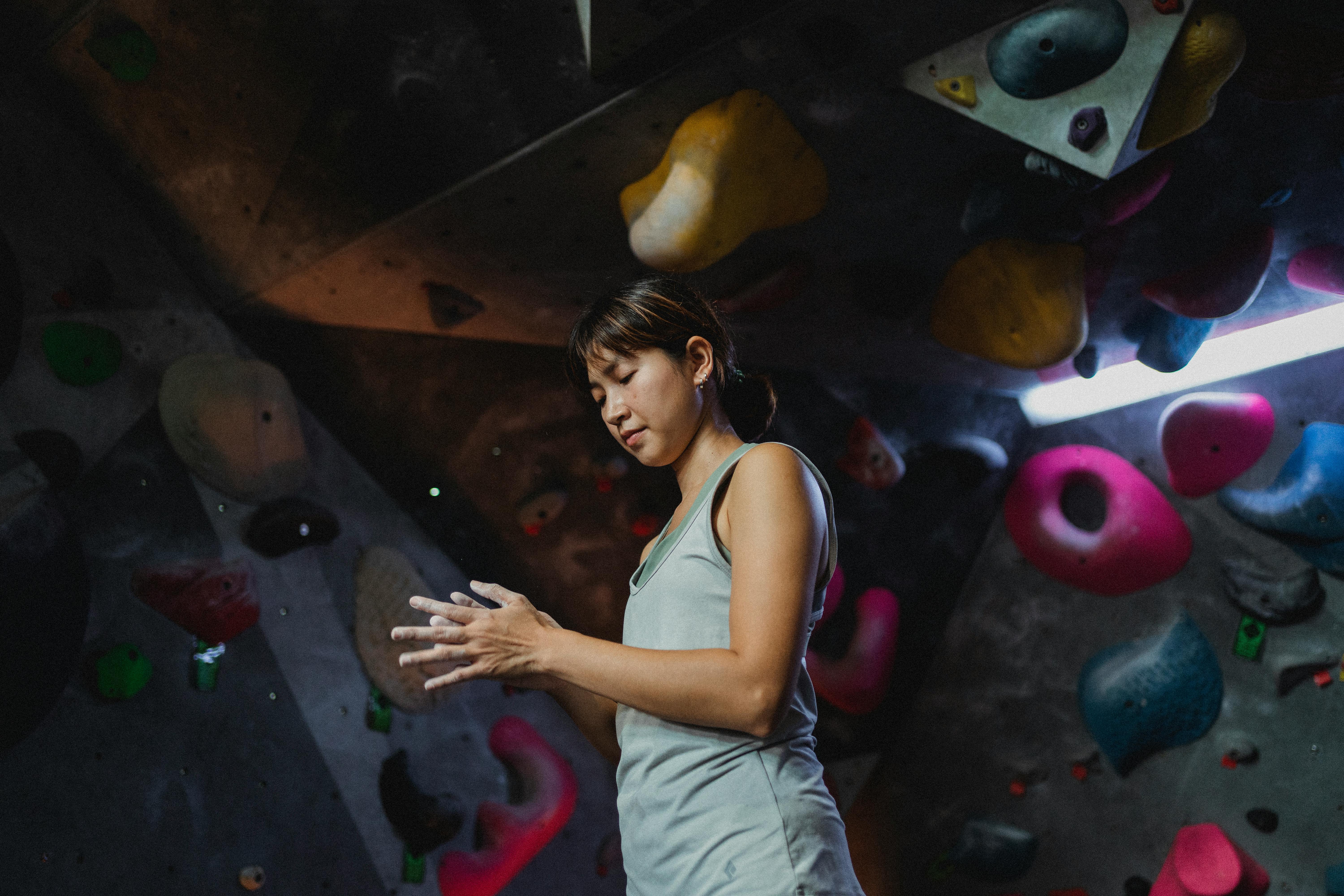 focused ethnic climber treats hands with talcum powder