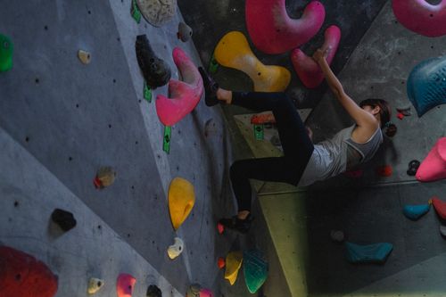 Free Low angle side view of determined alpinist climbing on wall during sports workout in bouldering gym Stock Photo