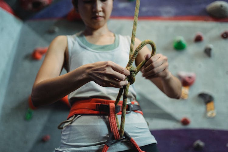 Strong Alpinist Tying Knot On Rope For Climbing