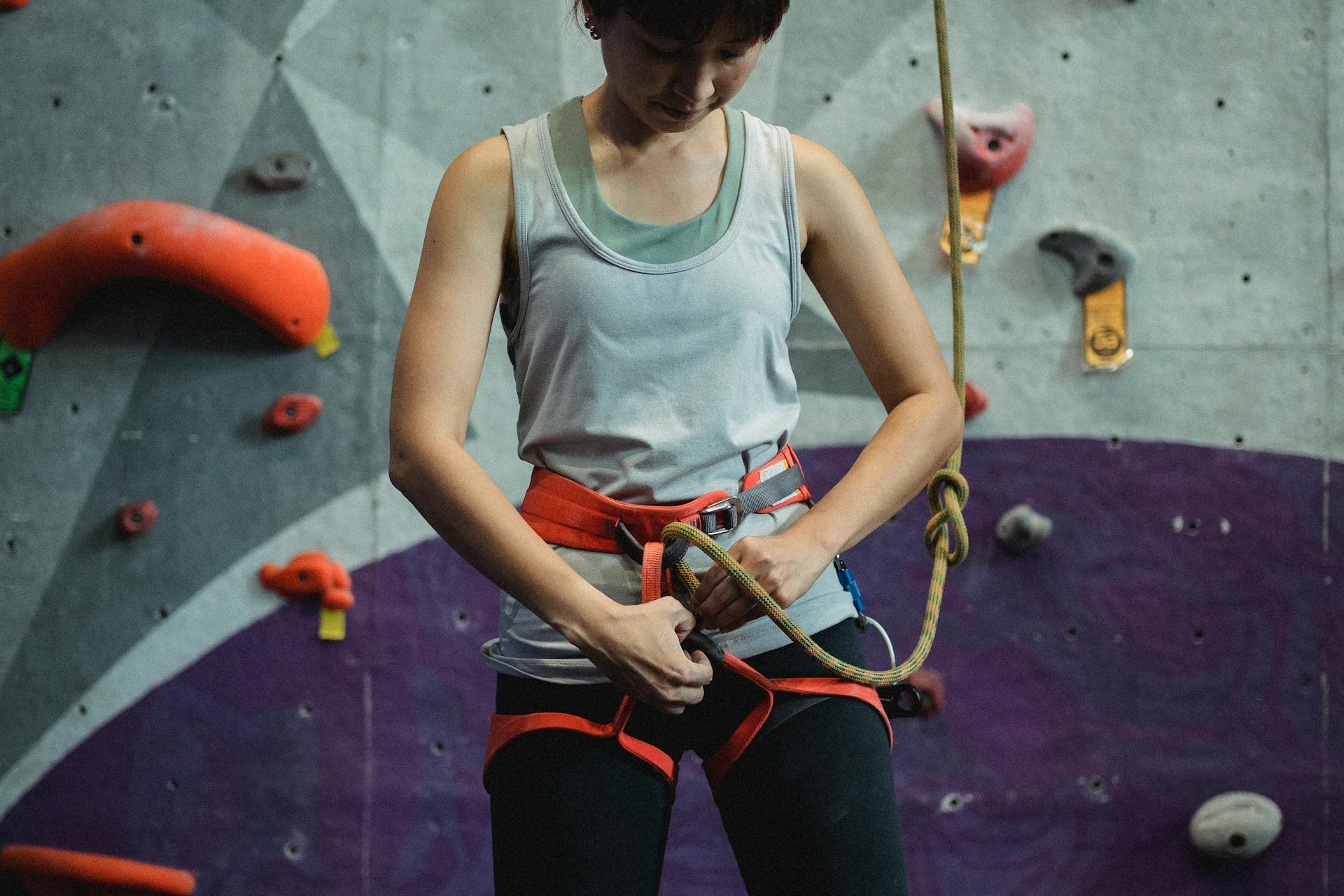 Crop female alpinist preparing climbing rope before ascending on wall during training in club