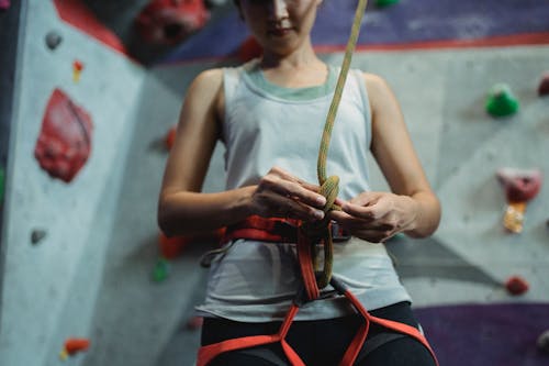 Crop female climber tying straps on safety belt