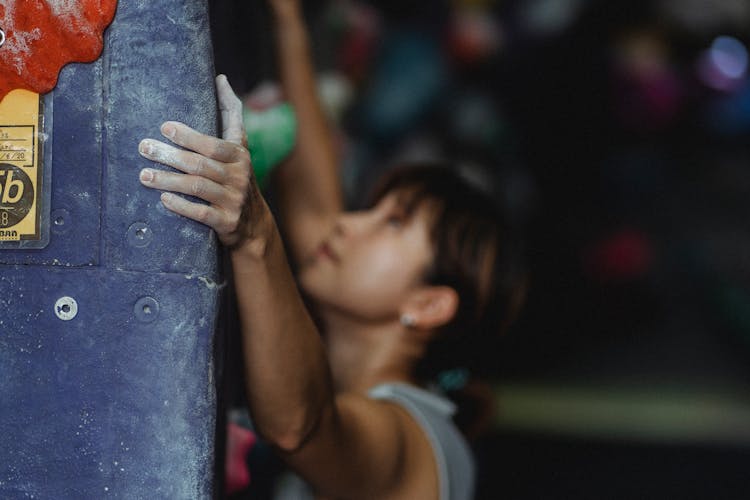 Concentrated Asian Female Climbing Wall In Bouldering Center