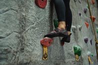 Unrecognizable climber ascending climbing wall during practice