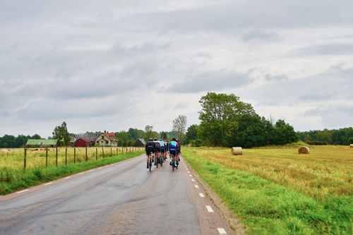 Free Group of cyclists enjoy a leisure ride on a scenic rural road surrounded by green fields. Stock Photo