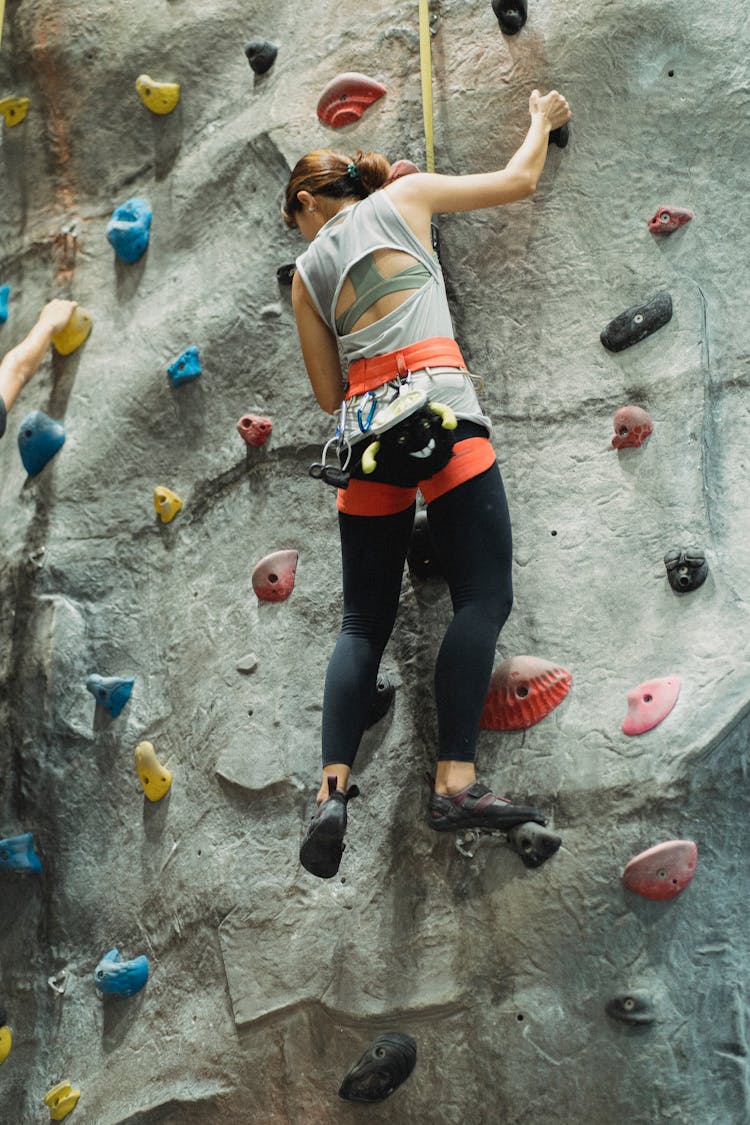 Woman Climbing On Wall In Climbing Center