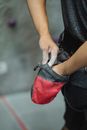 Crop faceless climber in sportswear standing in gym and preparing for bouldering while smudging hands in magnesia