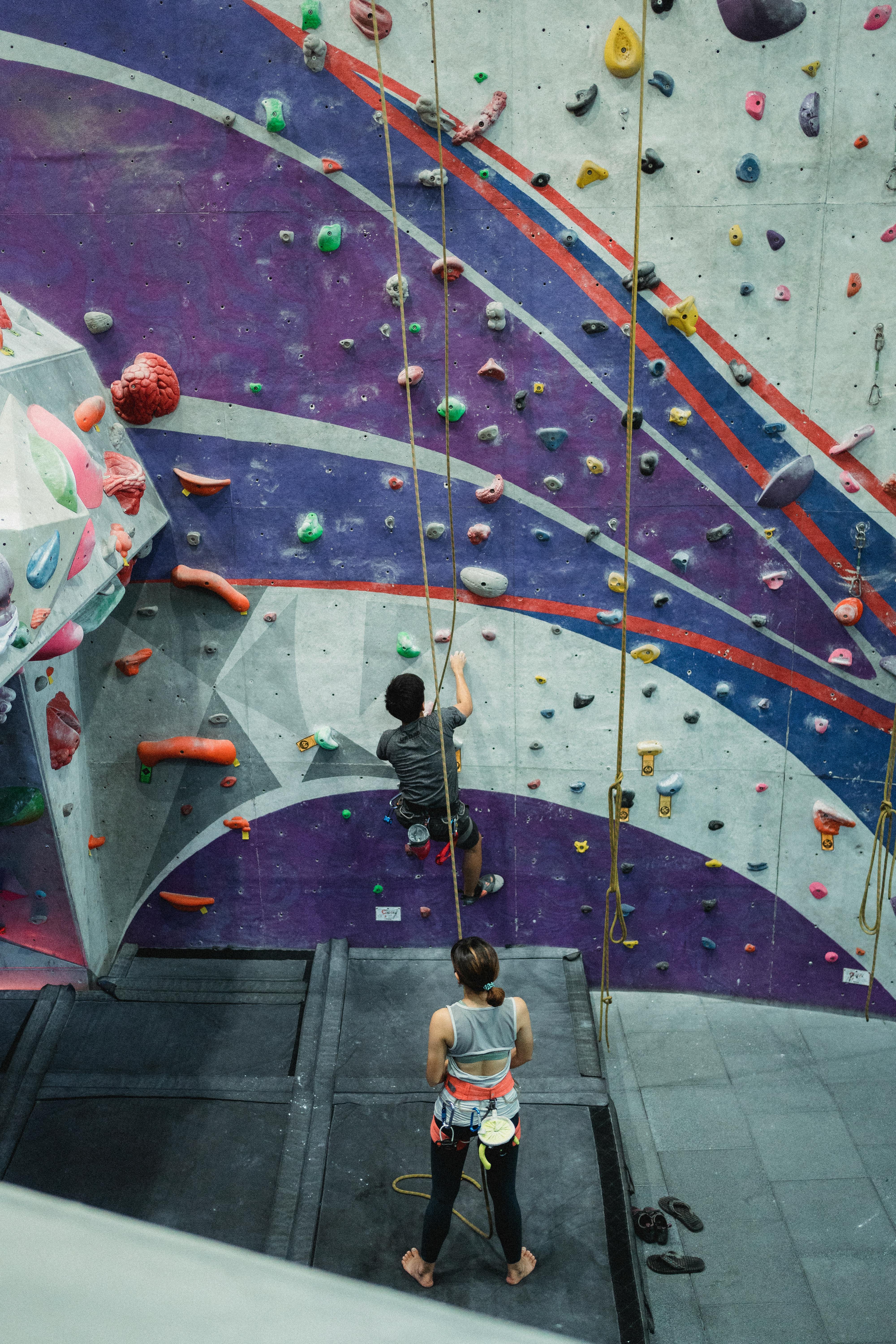 unrecognizable athletes climbing wall in gym