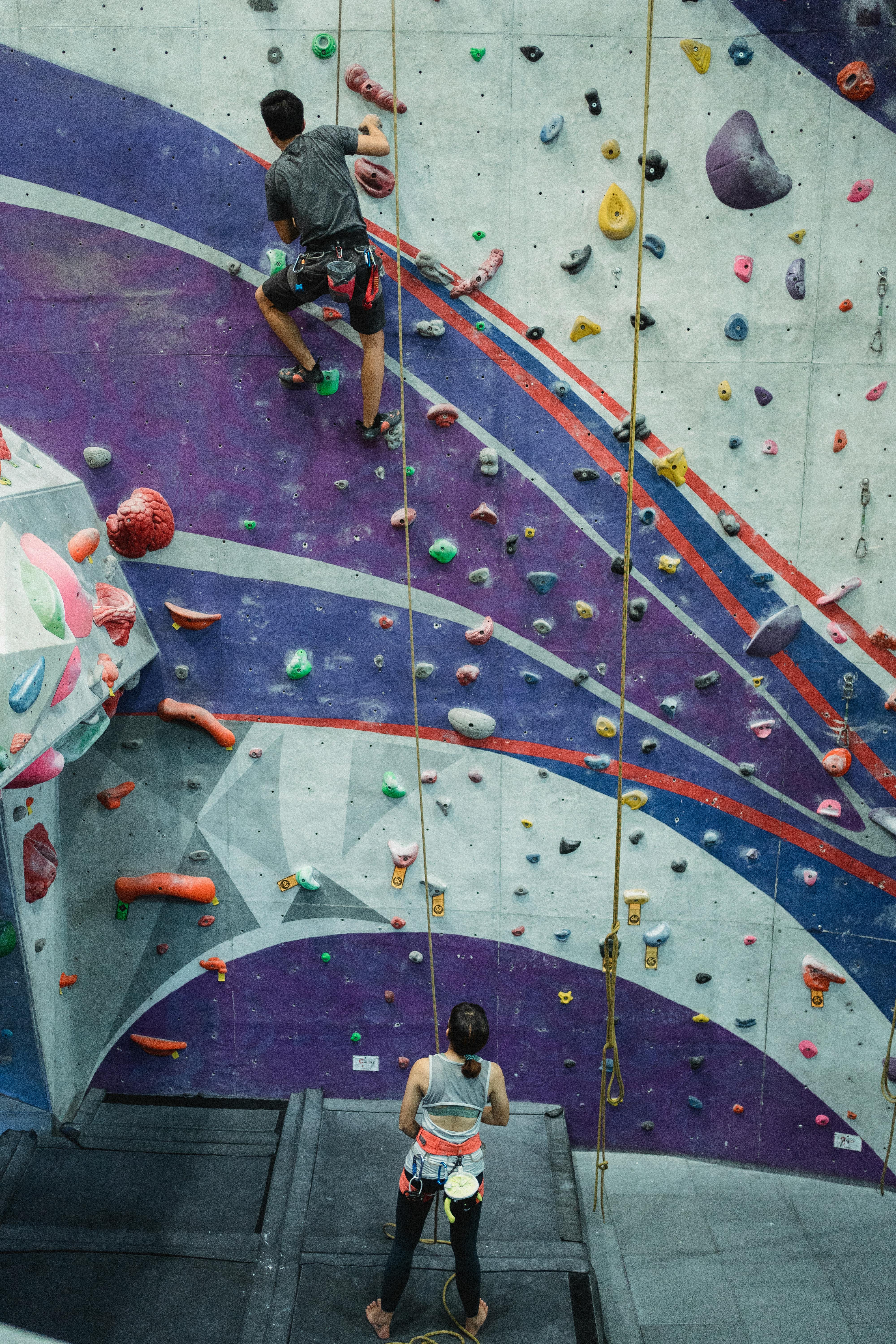 faceless man clambering wall with help of instructor