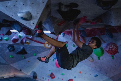 Free Side view of strong ethnic man practicing on climbing wall in modern bouldering center Stock Photo
