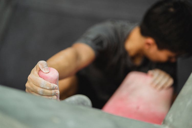 Anonymous Male Athlete Practicing Rock Climbing On Wall In Gym