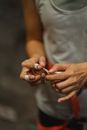 Crop unrecognizable female athlete dressed in activewear and belay sticking plasters around fingers for protection before climbing training in gym
