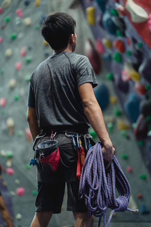Faceless athlete preparing rope for bouldering training in gym