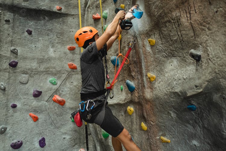 Strong Climber Preparing Climbing Wall With Screwdriver In Gym