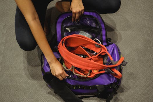 Woman packing climbing gear into a purple bag at an indoor gym, ready for a climbing workout.