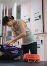Concentrated young Asian female athlete wearing black leggings getting ammunition out from violet sportive bag in changing room of gym