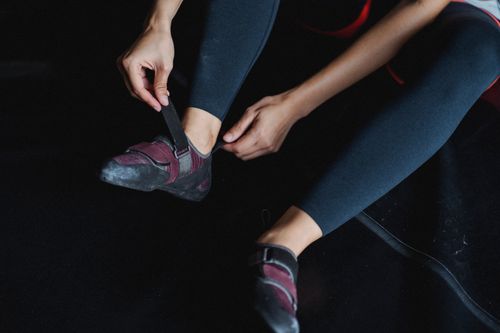 Free From above of crop faceless female athlete in leggings tying sneakers before workout in gym Stock Photo