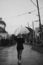 雨天，一位打着伞的匿名时尚女性漫步在城市道路上的黑白背影