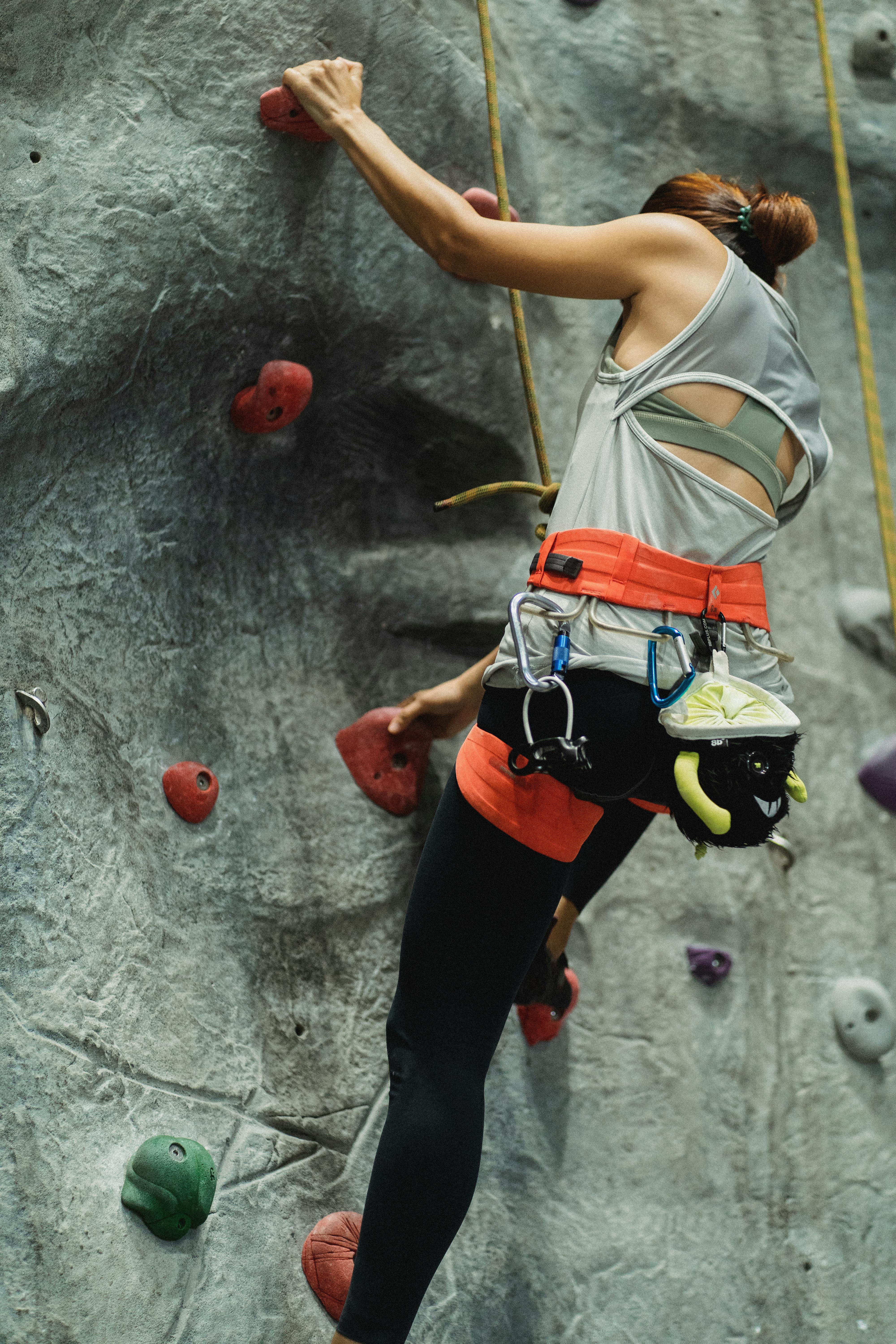 anonymous fit female alpinist practicing bouldering in climbing gym