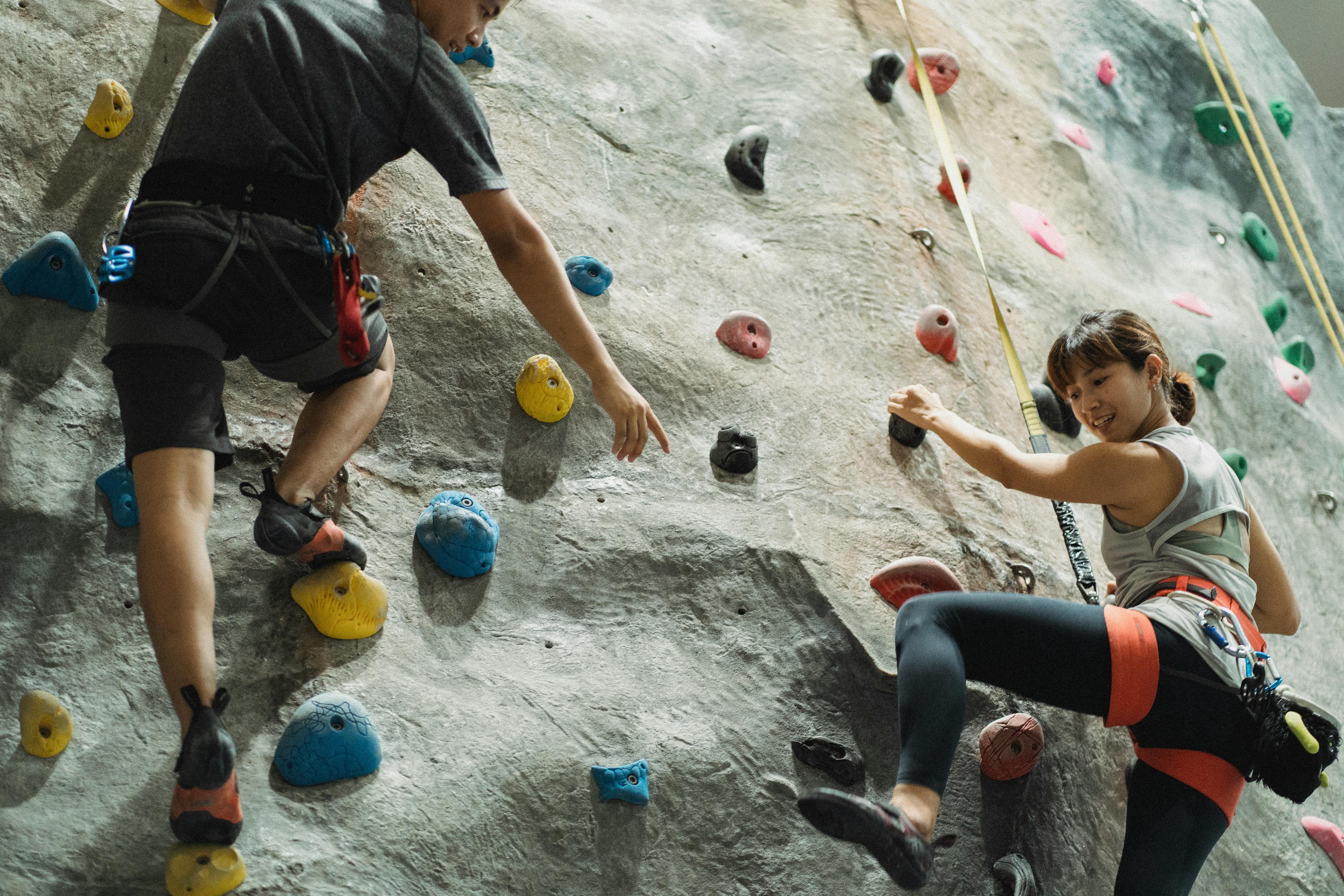 Two adults enjoying indoor rock climbing, showcasing strength and camaraderie.