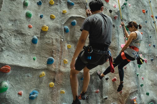 Anonymous mountaineers hanging on belay during climbing wall in gym
